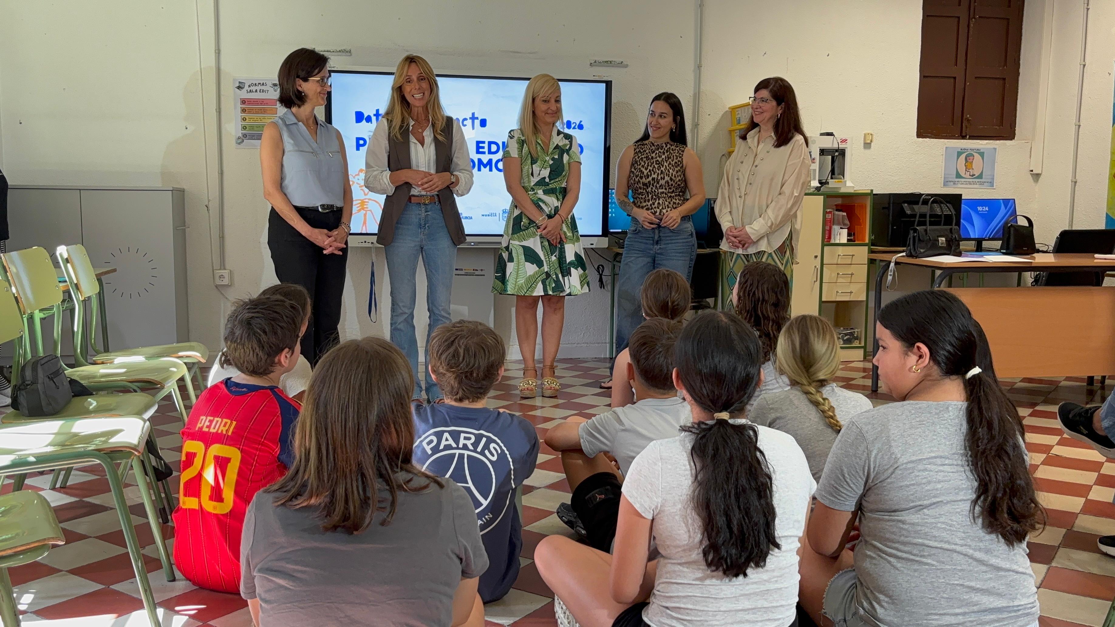 Autoriadades en el aula del colegio con alumnos sentados en el suelo